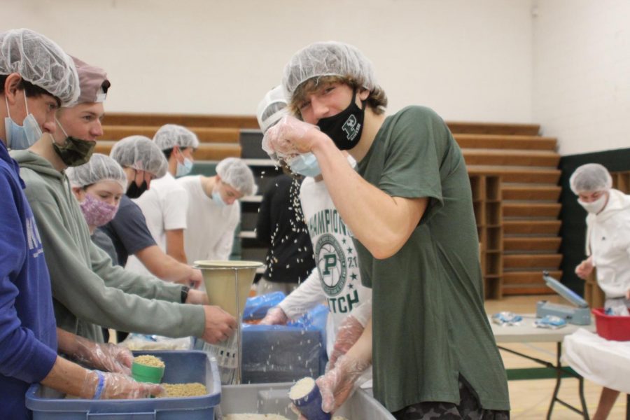 Junior Isaac Semini poses with rice while also packaging meals. 
