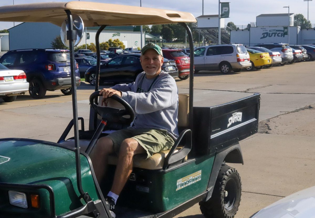 Retired US history teacher Bryant Hancock monitors the parking lot in a golf cart. He has taken on the responsibility of writing parking tickets in the Pella high school parking lot.